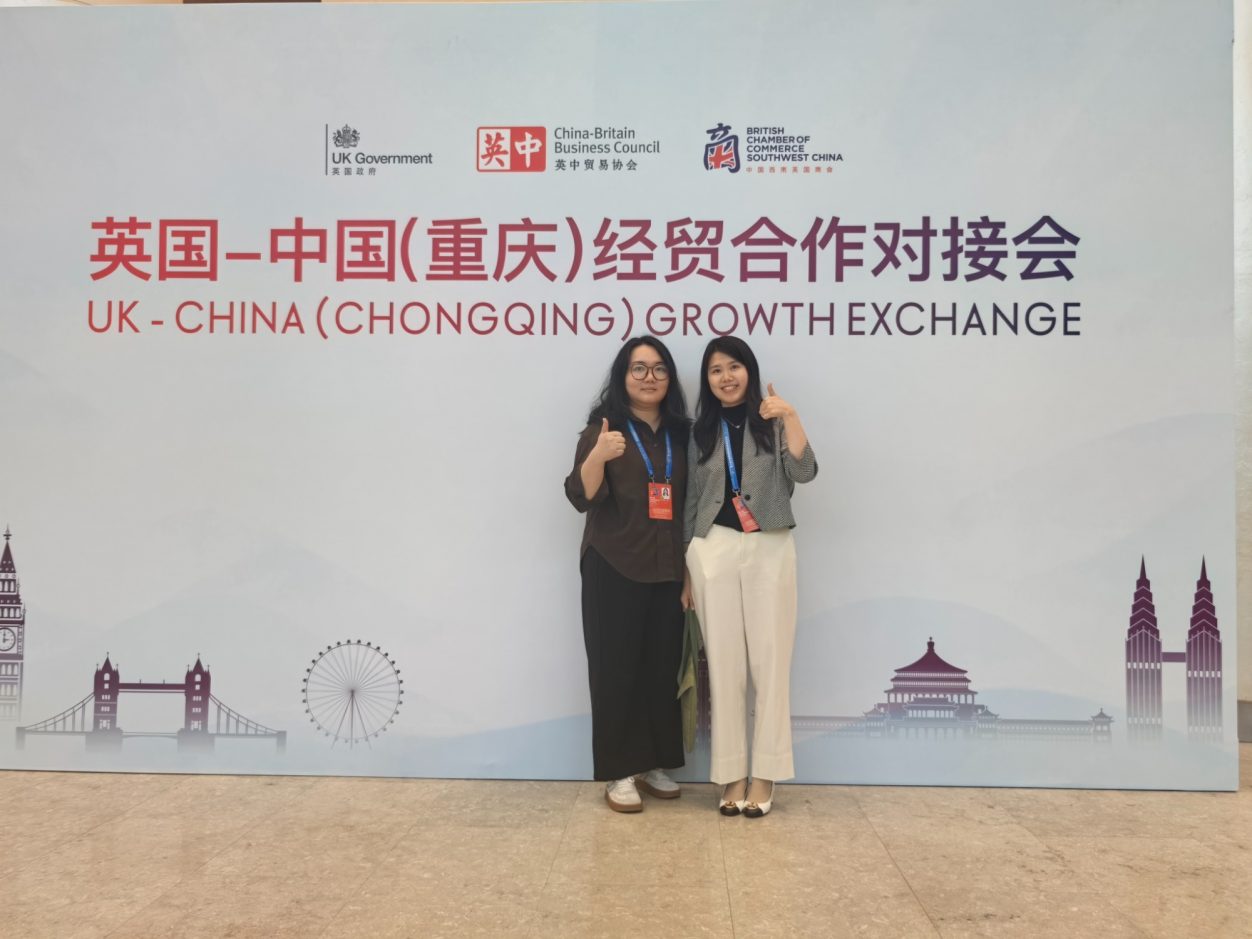 Thornhill Legal associtors in front of a banner for the UK-China (Chongqing) Exchange.