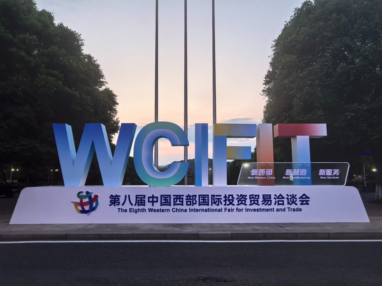 Large sign displaying "WCIF" with trees and a clear sky in the background.